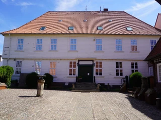 Museum Domherrenhaus Historisches Gebäude mit rotem Ziegeldach und weißer Fassade, umgeben von gepflastertem Hof.
