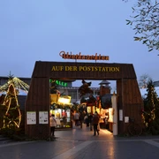 Weihnachtsmarkt in Langenfeld Weihnachtsmarkt-Eingang aus Holz mit Lichtern, Tannengirlanden und festlichem Schriftzug.