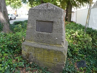 Lutherstein Steinmonument mit eingelassener Tafel in einer grünen Parkumgebung, dahinter Bäume und Fahrzeuge.