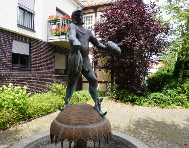 Störtebeker-Brunnen Brunnen mit einer Statue des Seeräubers Störtebeker in einer ruhigen Gartenanlage an einem gepflasterten Weg.