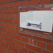 Eine Infotafel zum Stiftshof Verden an einer roten Ziegelwand mit Niedersachsen-Wappen.