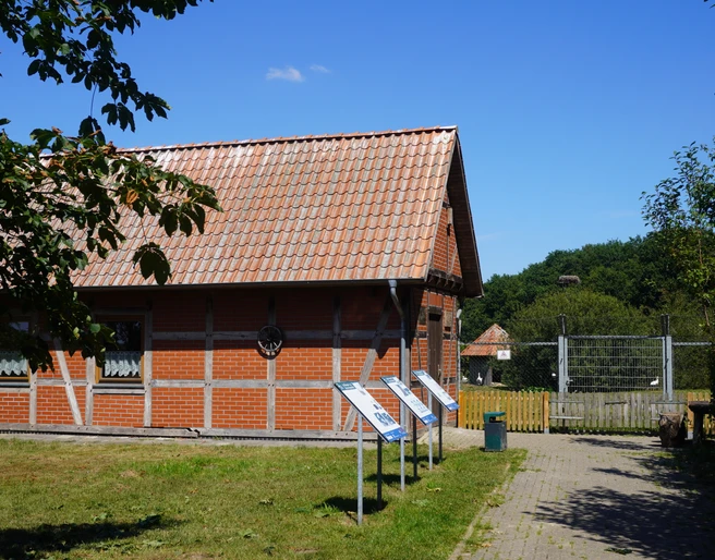 Storchenpflegestation Verden Storchenpflegestation in Verden mit Fachwerkgebäude, Infotafeln und grünem Umfeld unter blauem Himmel.