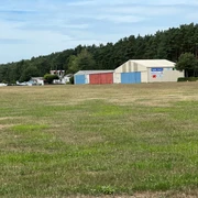Ein kleiner Flughafen mit angrenzenden Hangars und einem Wald im Hintergrund bei Verden, Scharnhorst.