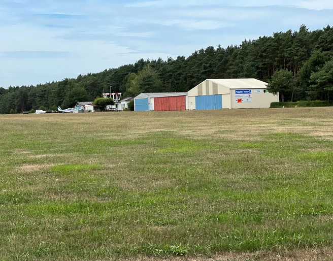Ein kleiner Flughafen mit angrenzenden Hangars und einem Wald im Hintergrund bei Verden, Scharnhorst.