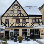 Café Welyn Fachwerkhaus mit Café und Eisdiele, beschneit, mit Schildern "Terrasse" und "Italienisches Eis", umgeben von winterlicher Atmosphäre.