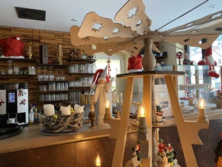 Café Welyn Counter Gemütlich dekorierter Tresen mit Weihnachtsdekoration, darunter eine Holzpyramide mit Kerzen, ein Adventskranz und Figuren in einer warmen Atmosphäre.