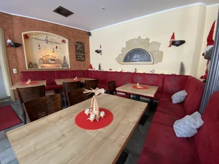 Café Welyn guest room Gemütliches Café mit roten Polsterbänken und Holztischen, weihnachtlich dekoriert mit Kerzen, Lichterketten und kleinen Figuren auf roten Tischsets.