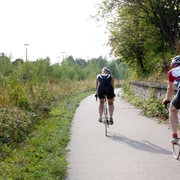 Unterwegs auf dem PanoramaRadweg niederbergbahn Zwei Radfahrende auf dem PanoramaRadweg Niederbergbahn, umgeben von grüner Natur und Bäumen.