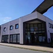 Modernes Hotelgebäude mit großflächigen Fenstern und einem winkeligen Eingangsbereich an der Straße.