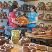 Zwei Frauen begutachten handgefertigte Keramikteller in einem Töpferladen.