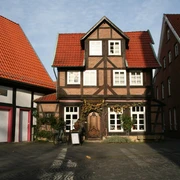 Weinhaus Ein traditionelles Fachwerkgebäude mit markantem roten Ziegeldach, begrüntem Eingang und dekorativem Türschild.