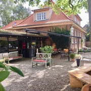 Eiscafé Bäk.jpg Blick vom Innenhof auf Sitzgelegenheiten vor dem Haus mit Tischen und Stühlen