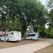 Wohnmobilstellplatz Bücken Wohnmobile stehen auf einem ruhigen Stellplatz unter hohen Bäumen, mit gepflasterten Wegen umgeben.