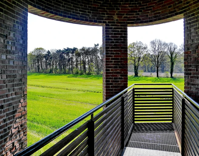 Landschaftsfenster Wemkendorf.JPG Blick durch einen Ziegelbogen auf grüne Wiesen und Bäume. Holzgeländer im Vordergrund.