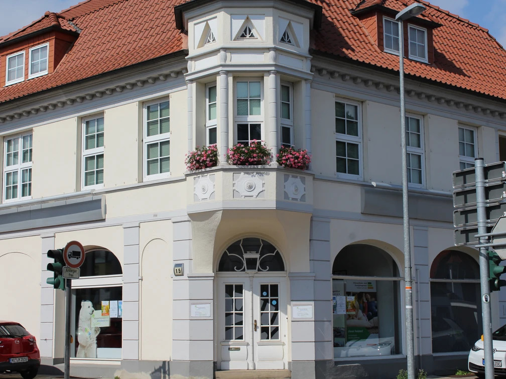 Eine zweigeschossige weiße Stadtvilla mit rotem Ziegeldach und dekorativem Erker zur Straßenecke.