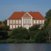 Kreismuseum Herzogtum Lauenburg.JPG Blick vom Ufer auf das Kreismuseum: rotes Gebäude mit weißen Fenstern, davor Wasser und Uferbereich mit Grün