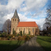 Historische Kirche St. Nikolaus, Backsteingotik mit markantem Turm, umgeben von grün gepflegter Anlage.