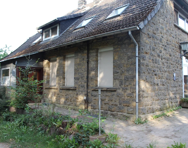 Rustikales Steinhaus mit weißen Fenstern und Schindeldach in grüner Umgebung in Münchehagen.