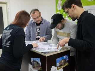 Mobile Rätselkiste - Freizeitaktivitäten in Leipzig  Mehrere Menschen sind mit über eine Box gebeugt und sind mit dem lösen einer Rätselkiste beschäftigt