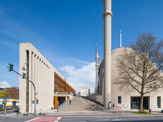 Central Mosque Cologne Im Vordergrund erhebt sich die Zentralmoschee Köln mit ihrer imposanten Fassade und Minaretten; links der moderne, rechtwinklige Vorbau.In the foreground is the Central Mosque of Cologne with its imposing façade and minarets; on the left is the modern, rectangular porch.