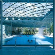 Geibeltbad Pirna Geibeltbad Pirna: Modernes Hallenbad mit Glasdach, blauem Wasser und mehreren schwimmenden Personen; helle, luftige Atmosphäre mit Pflanzen und Liegestühlen.