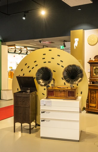Espelkamp-Schloss Benkhausen-Automatenmuseum-Teutoburger-Wald-Tourismus-D-Ketz-076-CC-BY-SA.jpg Ein Ausstellungsraum mit antiken mechanischen Musikgeräten, darunter Grammophone und Musiktruhen.