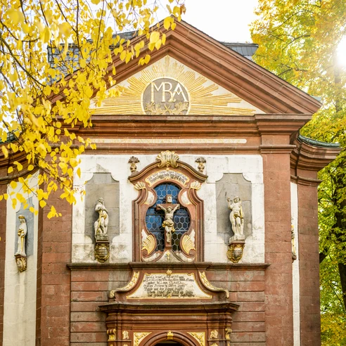 Lichtenau-Kirche Maria Heimsuchung-Teutoburger-Wald-Tourismus-D-Ketz-058-CC-BY-SA.jpg Barockkirche mit verzierten Fassaden, herbstlichen Bäumen und strahlender Sonne im Hintergrund.
