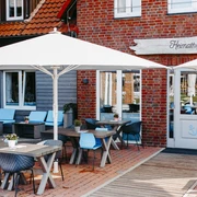 Heimathafen Außenbereich eines Restaurants im maritimen Stil mit Holztischen, blauen Stühlen und Sonnenschirmen.