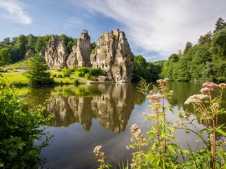 Horn-Bad Meinberg-Externsteine-Teutoburger-Wald-Tourismus-D-Ketz-055-CC-BY-SA.jpg Bizarr geformte Sandsteinfelsen spiegeln sich in einem malerischen See, umgeben von grüner Natur.