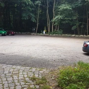 Wanderparkplatz Garrensee  Sandparkplatz mit parkenden Autos. Im Hintergrund stehen Bäume
