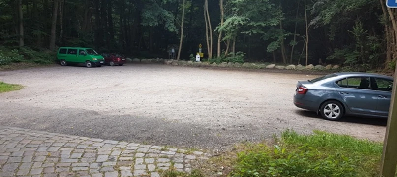 Wanderparkplatz Garrensee  Sandparkplatz mit parkenden Autos. Im Hintergrund stehen Bäume