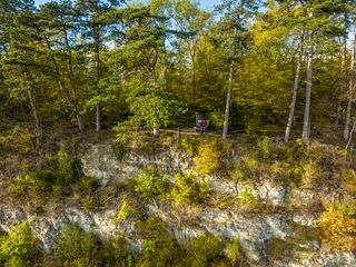 Hoexter-Rabenklippen-Teutoburger-Wald-Tourismus-D-Ketz-108.jpg Eine bewaldete Klippe, auf der ein Paar auf einer Bank sitzt, umgeben von herbstlichen Bäumen.