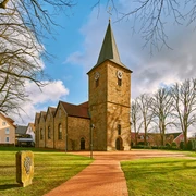 Ehemalige Kirche Hagen Außenansicht Großflächiger Platz mit Kirche im Sonnenschein, umgeben von Bäumen und historischen Gebäuden.