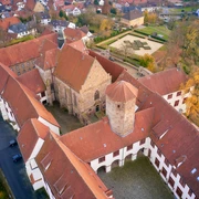 Luftaufnahme eines historischen Klosterkomplexes mit roten Ziegeldächern und Herbstbäumen.