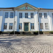 Kreisarchiv2_Silvana Dust_20230228.jpg Das Kreisarchiv Ratzeburg von außen, weißes Gebäude mit Wappen oben im Vorsprung