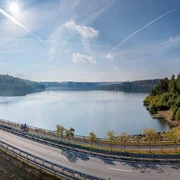 BadWuennenberg–Aabachtalsperre-Teutoburger-Wald-Tourismus-Patrick-Gawandtka-038-CC-BY-SA.jpg Stausee mit Radweg im Vordergrund, umgeben von dichtem, grünen Wald unter klarem blauen Himmel.Stuwmeer met fietspad op de voorgrond, omgeven door dicht, groen bos onder een strakblauwe hemel.Reservoir with cycle path in the foreground, surrounded by dense, green forest under a clear blue sky.