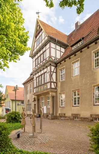 Fachwerkgebäude mit verziertem Giebel, dekorativer Fassade und Skulpturen auf einem Pflasterplatz.