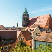 Blick zur Marienkirche Blick auf eine historische Stadt mit roten Ziegeldächern und einem großen Kirchturm unter klarem, blauem Himmel.