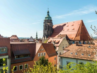 Blick zur Marienkirche Blick auf eine historische Stadt mit roten Ziegeldächern und einem großen Kirchturm unter klarem, blauem Himmel.