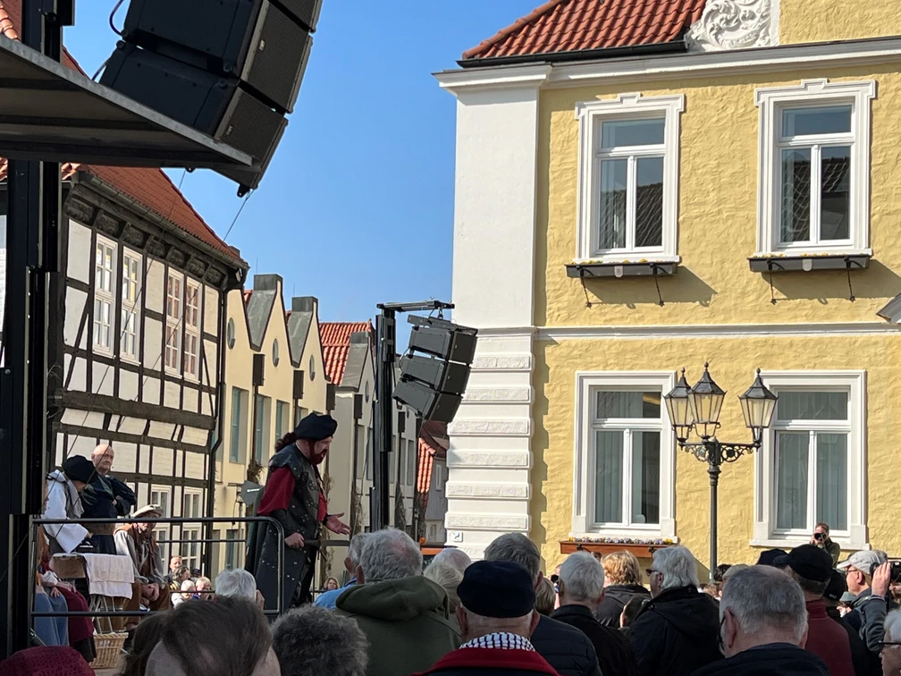 Läthare Spende Verden Ein mittelalterlich gekleideter Redner spricht zu einer Menge vor der historischen Kulisse Verdens.