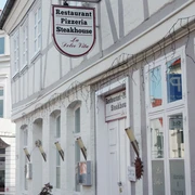 La-Dolce-Vita---Bernadette-Raffenberg-09.03.jpg Ansicht eines weißen Hauses mit einem Schild, auf dem „Restaurant-Pizzeria-Steakhouse“ steht