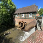 Wassermühle Meyenburg Mühlenrad der Wassermühle Meyenburg mit Bach und Mühlengebäude.