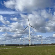Windräder drehen sich auf der Paderborner Hochfläche unter einem bewölkten Himmel in einer grünen Landschaft.