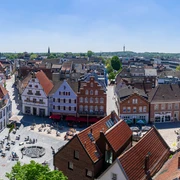 Rheine_Marktplatz03_Bildrechte EWG Rheine.jpg Panorama des belebten Marktplatzes in Rheine mit historischen Gebäuden und Menschen im Freien.