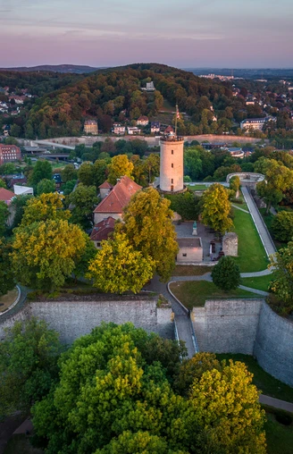 Bielefeld-Sparrenburg-Teutoburger-Wald-Tourismus-D-Ketz-008.jpg <p>Luftaufnahme der Sparrenburg Bielefeld, umgeben von grünen Bäumen, im Sonnenuntergang.</p>