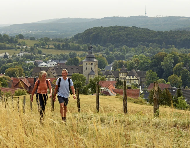 Bad-Driburg-Neuenheerse-Teutoburger-Wald-Tourismus-F-Grawe (14).JPG Zwei Wanderer auf einem Feldweg mit Blick auf Neuenheerse und die waldige Hügellandschaft.