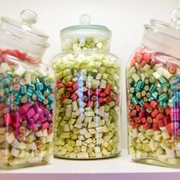 Dosen voller Bonbons Drei Glasbehälter mit bunten Bonbons in Rot, Grün und Blau auf einem Regal; die Atmosphäre wirkt nostalgisch und einladend.