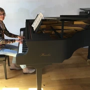 Annette Liss am Haessler-Flügel Die Pianistin Annette Liss sitzt am Klavier und lächelt in die Kamera.