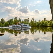 Weiße Flotte, Mülheim an der Ruhr Schiff der Weißen Flotte auf der Ruhr, umgeben von grünen Bäumen und einer Brücke rechts im Bild.