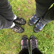 Wandern  Drei Paar Wanderschuhe stehen auf grüner Wiese, bereit für ein Abenteuer im Freien.